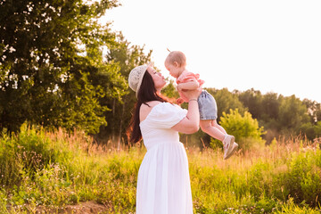 Lifestyle mother and child in casual clothes playing together in chamomile field