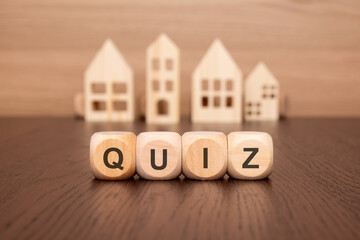 wooden cubes on a table with text QUIZ, model house on background