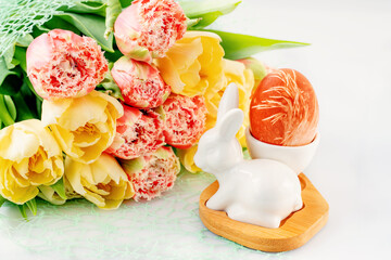 Easter composition on a light background. Cute white rabbits, yellow and pink tulips, Easter eggs symbol of the Easter holiday. Home and office decoration. Happy Easter holiday