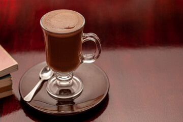 Glass cup-type mug with hot, foamy chocolate.