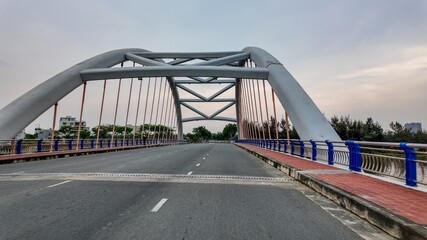 Fototapeta premium Empty modern arch bridge over a smooth-flowing river, symbolizing connectivity and urban infrastructure development at dawn