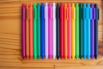 Obraz premium Multi-colored pens are stacked on a black desk in the designer's office in preparation for a quick and easy choice of design colors. Lots of colorful pen backgrounds for designers and designers.