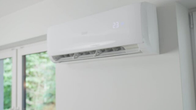 Hand adjusting temperature on air conditioner with remote control, Working air conditioner for comfort temperature in living room at hot summer