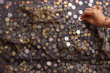 The blurry and dark background of the wall is adorned with international coins affixed to the walls...