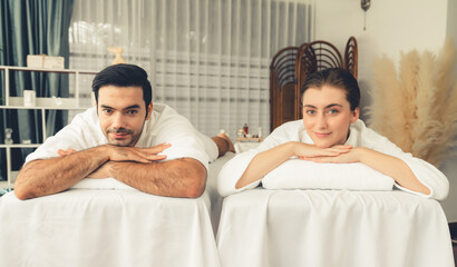 Fototapeta premium Caucasian couple customer enjoying relaxing anti-stress spa massage and pampering with beauty skin recreation leisure in day light ambient salon spa at luxury resort or hotel. Quiescent
