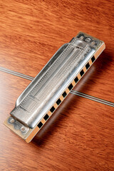 
Vintage 10-hole diatonic harmonica rest on the back of an upturned acoustic guitar

