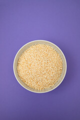 Coconut flakes in white small bowl on yellow
