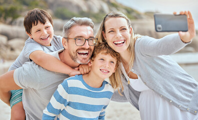 Parents, children and selfie at beach with smile, excited and bonding for love on vacation in summer. Father, mother and kids on holiday for memory, embrace or social media for piggy back in sunshine