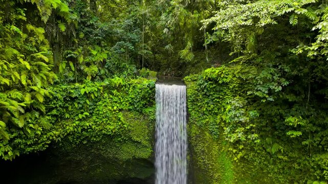 Aerial view of Tibumana waterfall, a beautiful hidden waterfall in rainforest, Bali, Indonesia.  Tibumana Waterfall referred to by locals as Air Terjun Tibumana is one of the most beautiful place.