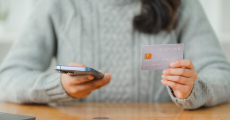 Close-up of woman holding mobile phone and credit card in her hands she paying online for bills