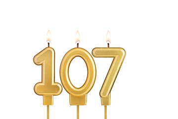 Golden number 107 birthday candle on white background
