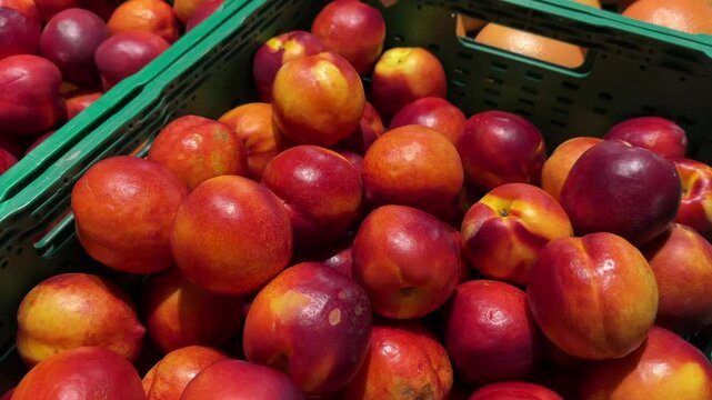 Ripe nectarines in a green crate at a market.