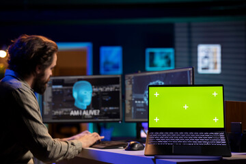 Programmer being asked existential questions by awaken AI gaining consciousness, green screen laptop. Man communicating with artificial intelligence emulating humans, mockup notebook