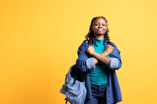 Assertive african american woman shows letter X with arms crossed, staying in warrior stance, showing fierceness. Firm BIPOC person using negative body language to signal rejection, studio background