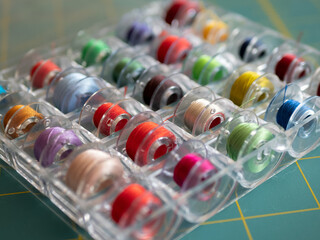 Bobbins with colored threads in the plastic box for storage. Sewing accessories concept