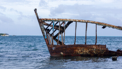 Rustic abandoned boat on the edge of the beach of in la guajira colombia under the blue cloudy sky