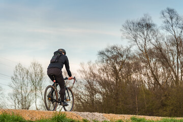 Naklejka premium Cyclist conquers gravel path amidst nature serenity, perfect for fitness, eco-friendly lifestyle themes