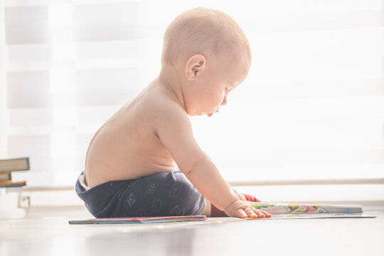 Portrait of bbaby looks at a educational book. Intellectual development of newborns.