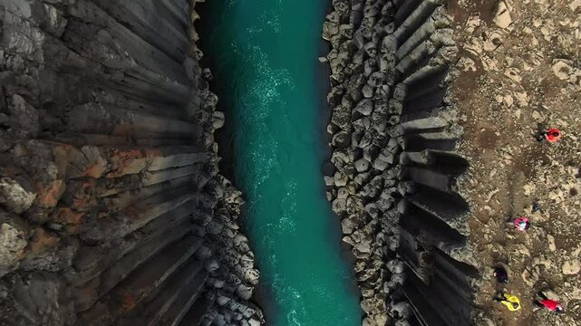 aerial top down view drone shot of basaltic rock formation, studlagil canyon,clean river water runs in the gorge,icelandic wild nature