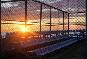 Fototapeta premium View of a children's soccer field. Green lawn of football field. Football field. artificial grass. Sunset time. Batumi, Georgia. white lines. stadium with many plastic seats.