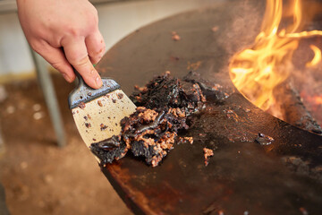 Enjoying grilling in the backyard and using a scraper to clean off burnt residue from the fire pit