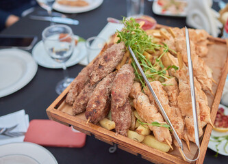 Savor tasty Meat Skewers and crispy Fries on a Wooden Platter at an Outdoor Dining Event