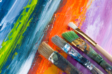Fototapeta premium Various Paint Brushes on Colorful Abstract Canvas Background