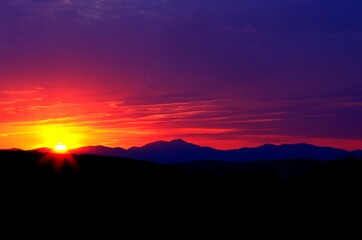 The Sun And Colored Sky Over Mountain Range