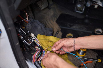 Closeup image featuring hands fixing electrical wires in a car for maintenance and repair