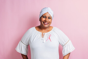 Woman breast cancer survivor with white turban on her head and pink ribbon on her chest.