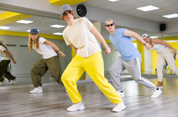 Stylish boys and girls dancing synchronous group choreography in dance hall