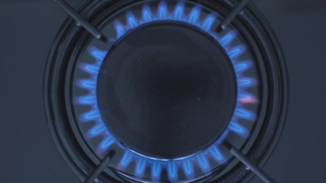 Kitchen burner turning on.Stove top burner igniting into a blue cooking flame.  Natural gas inflammation, close up, slow motion.
