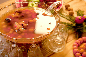 Punch bowl full of tropical fruit punch and cups around it.