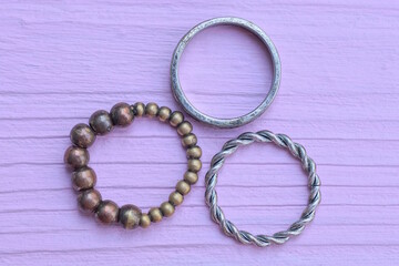 three copper and silver rings lie on a pink wooden table