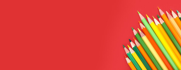 Fototapeta premium Color pencils on red background, closeup