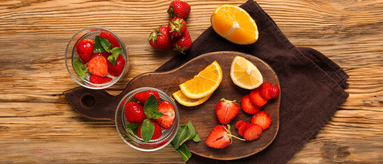 Glasses of infused water with strawberries and mint on wooden background