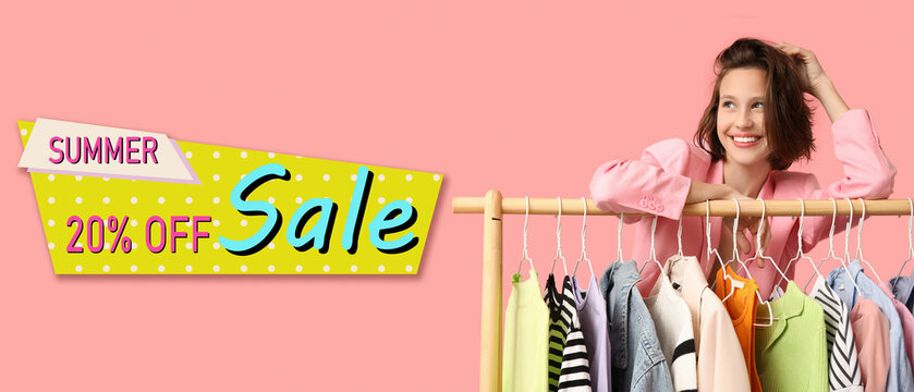 Beautiful young woman near rack with different clothes on pink background