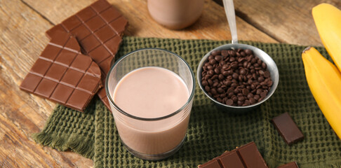 Glass of sweet chocolate milk on wooden table