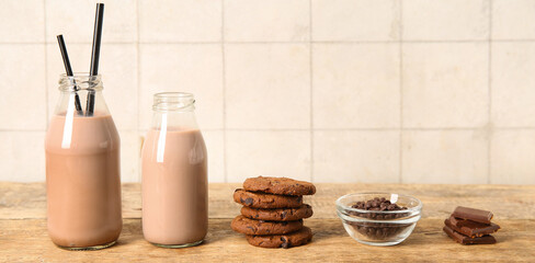 Bottles of sweet chocolate milk and tasty cookies on wooden table