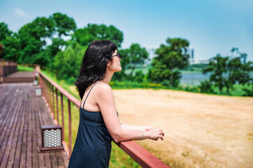 50 years old russian woman in short dress holding her sunglasses on the summer day