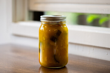 A quart sized glass jar filled with homemade mustard pickles and onions. The yellow sauce has...