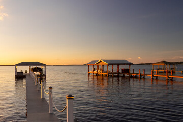 Multiple floating docks with custom wooden shelters, awnings, and lifts for protecting recreational...