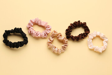 Set of different silk scrunchies on color background
