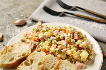 Plate of tasty Olivier salad with bread on grunge background, closeup