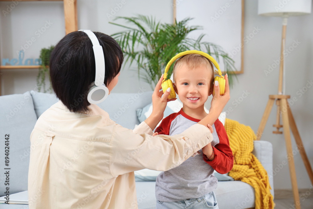 Wall mural young mother and her little son in headphones at home