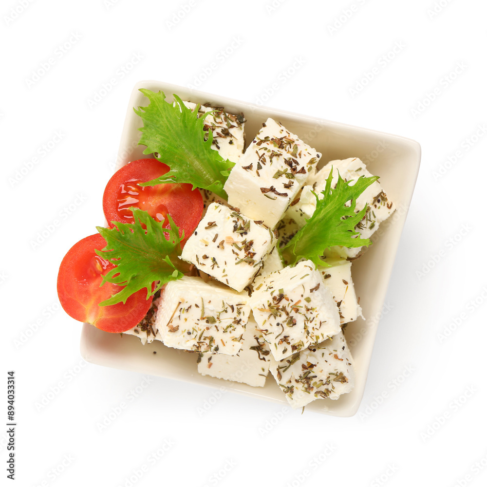 Wall mural bowl with tasty cut feta cheese, spices, salad leaves and tomatoes on white background