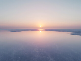 Fototapeta premium A beautiful sunset over a calm ocean. The sky is a mix of pink and blue hues, creating a serene and peaceful atmosphere. The water is still, reflecting the colors of the sky and the sun