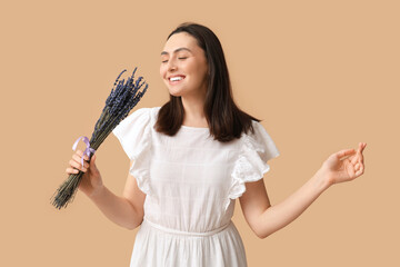 Beautiful happy young woman with bouquet of lavender flowers on beige background