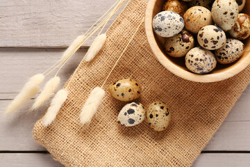 Bowl with quail eggs and dried lagurus on grey wooden background