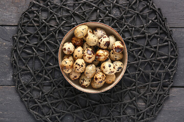 Place mat and bowl with quail eggs on black wooden background